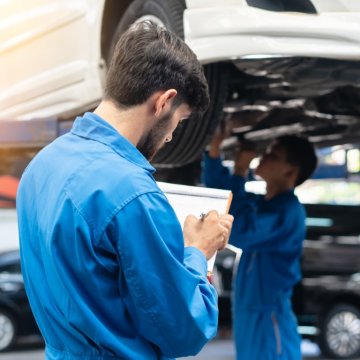 car tech looking over a vehicle on a hoist